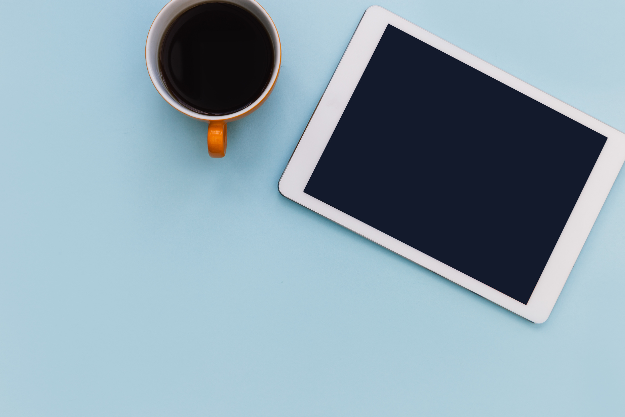 White Tablet Computer with Coffee Cup on Blue Color Background