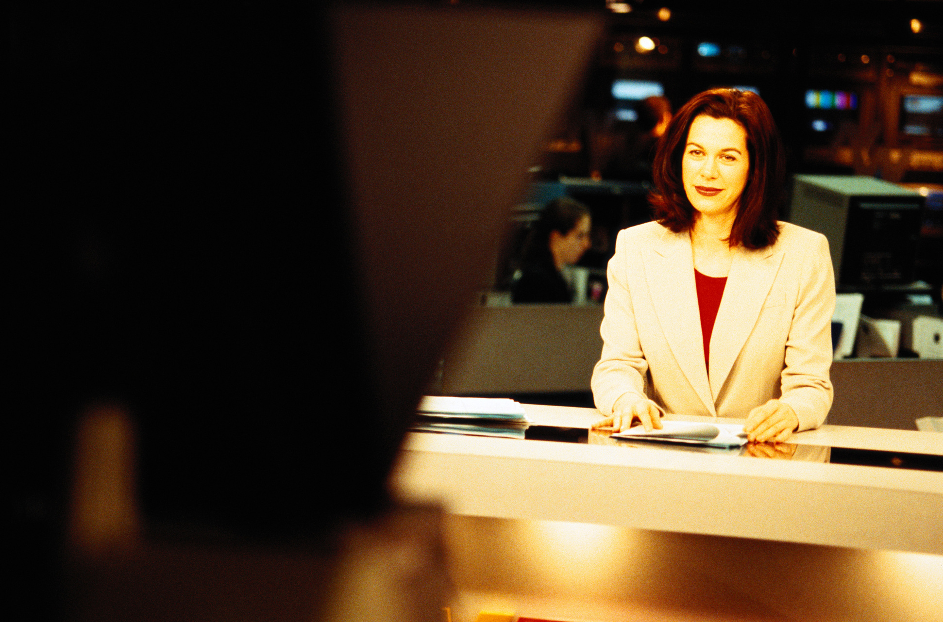 Television anchorwoman sitting at desk smiling at camera
